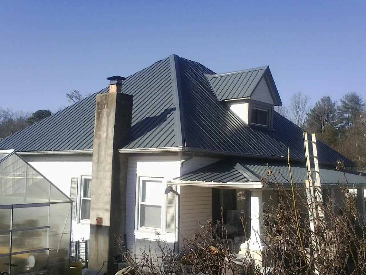 Dark blue standing seam metal roof on a white farmhouse with dormer — Slate & Tile Roof Repair by Roofing Brothers in Leesport
