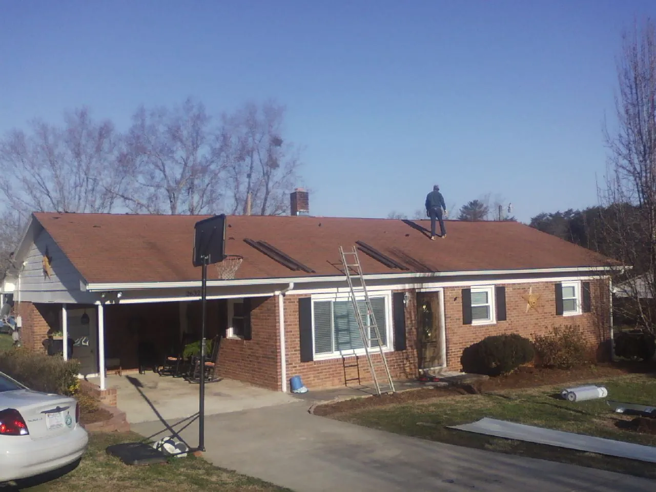 Roofer stripping a shingle roof on a brick ranch before metal panels in Leesport