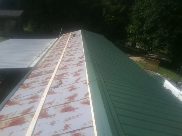 Old rusted panels beside newly installed green metal roofing — Wind Damage Roof Repair by Roofing Brothers in Leesport