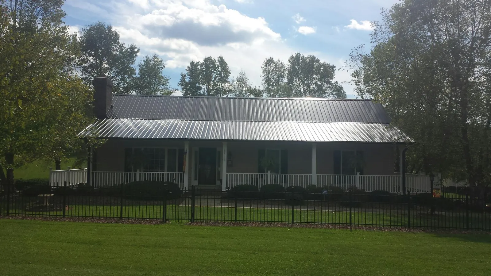 Gray metal roof on a brick ranch with a full width front porch — Gutter Guard Installation work by our crew in Leesport