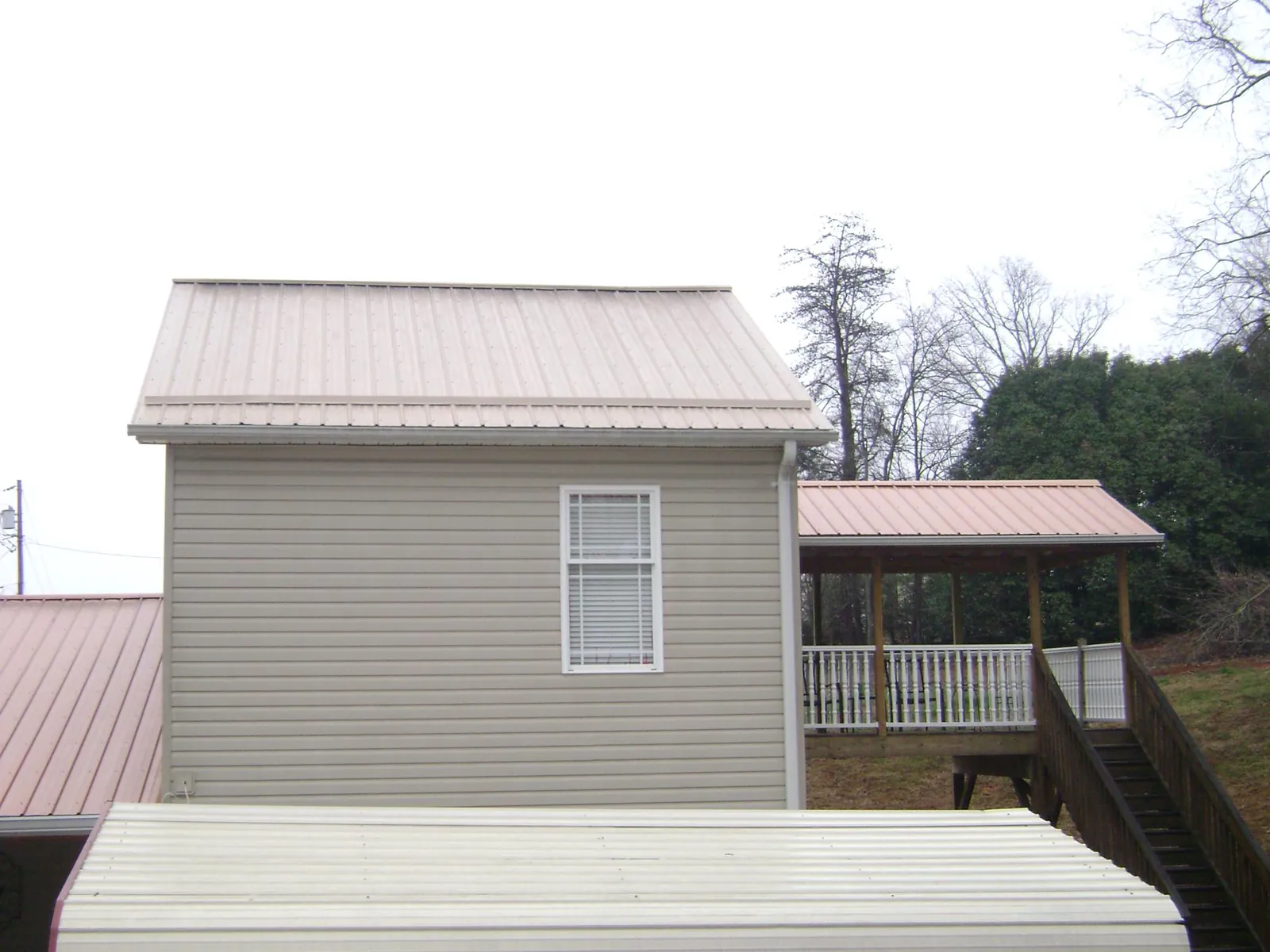 Tan metal roofs on a two story addition and attached porch, from a Roof Replacement job in Leesport