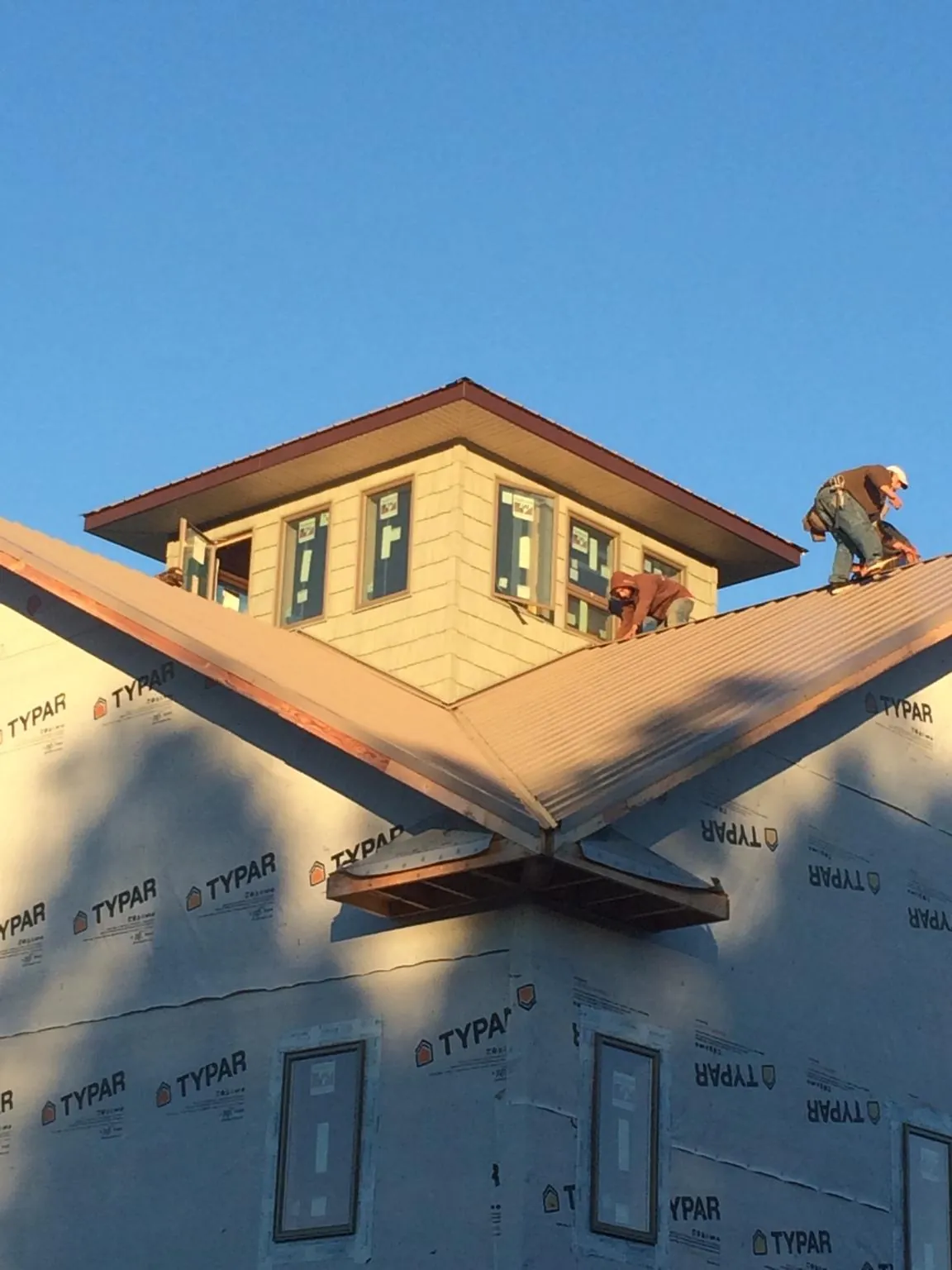 Roofers working around a rooftop cupola on a new metal roof at sunset — Roof Waterproofing in Leesport by Roofing Brothers